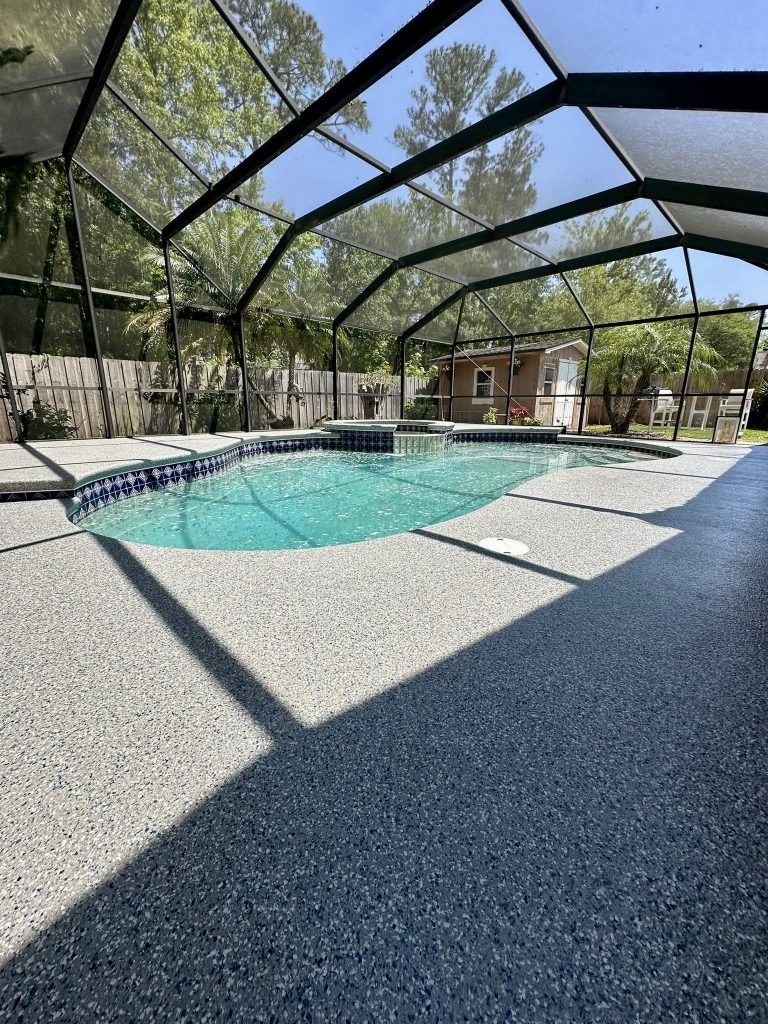 Pool deck with blue-gray coating surrounding a kidney-shaped pool