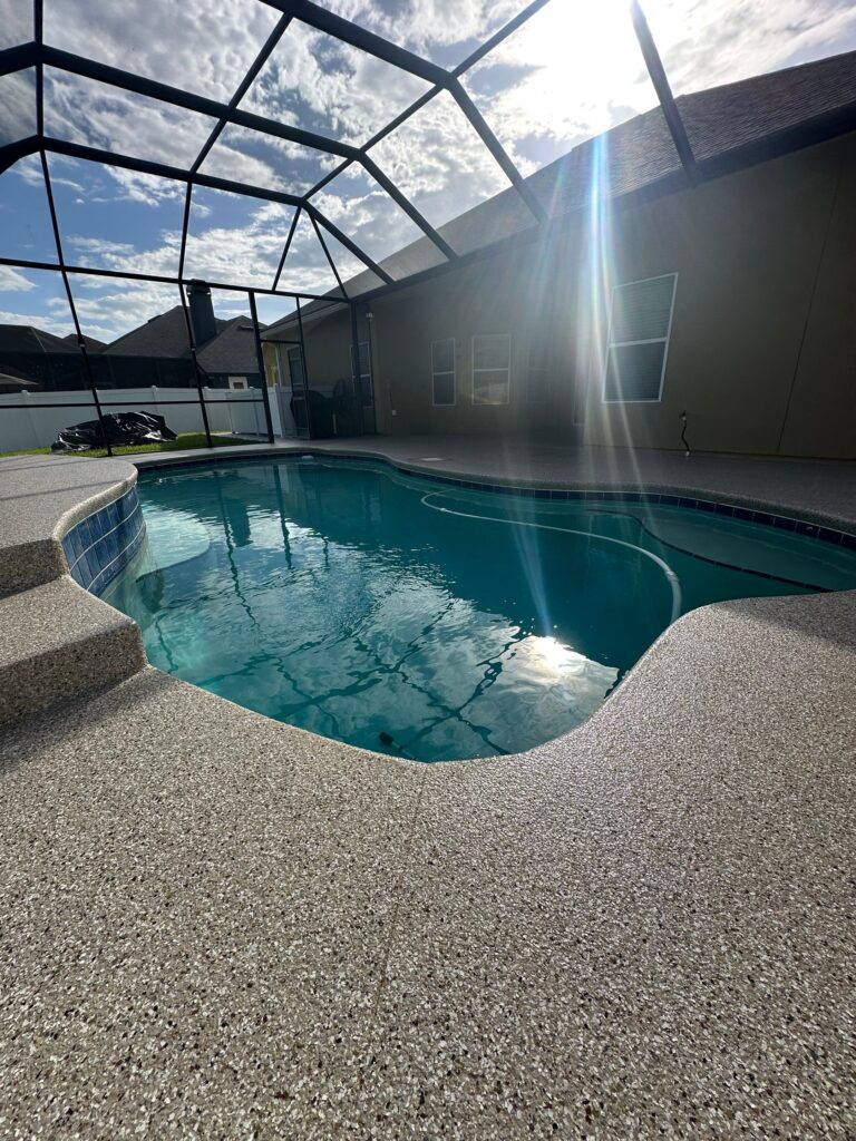 Concrete pool deck with beige coating and screened enclosure