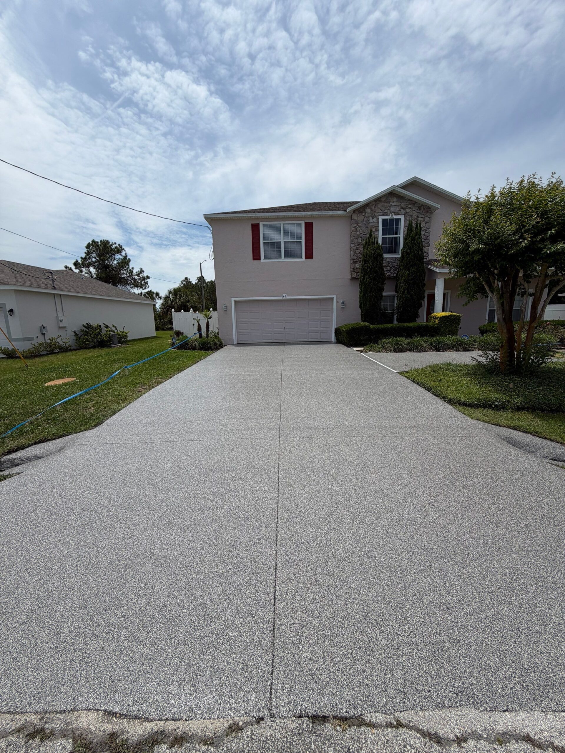 Resurfaced concrete driveway with flake polyurea coating, front of home